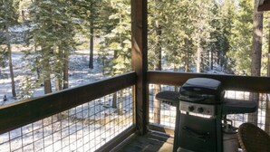 A covered outdoor area with a grill and a view of a snowy forest. - Spacious Studio Loft | Fireplace + Private Balcony (Truckee)