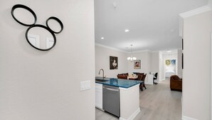 A modern kitchen with a blue countertop, white cabinetry, and a dining area with a brown sofa and chairs.