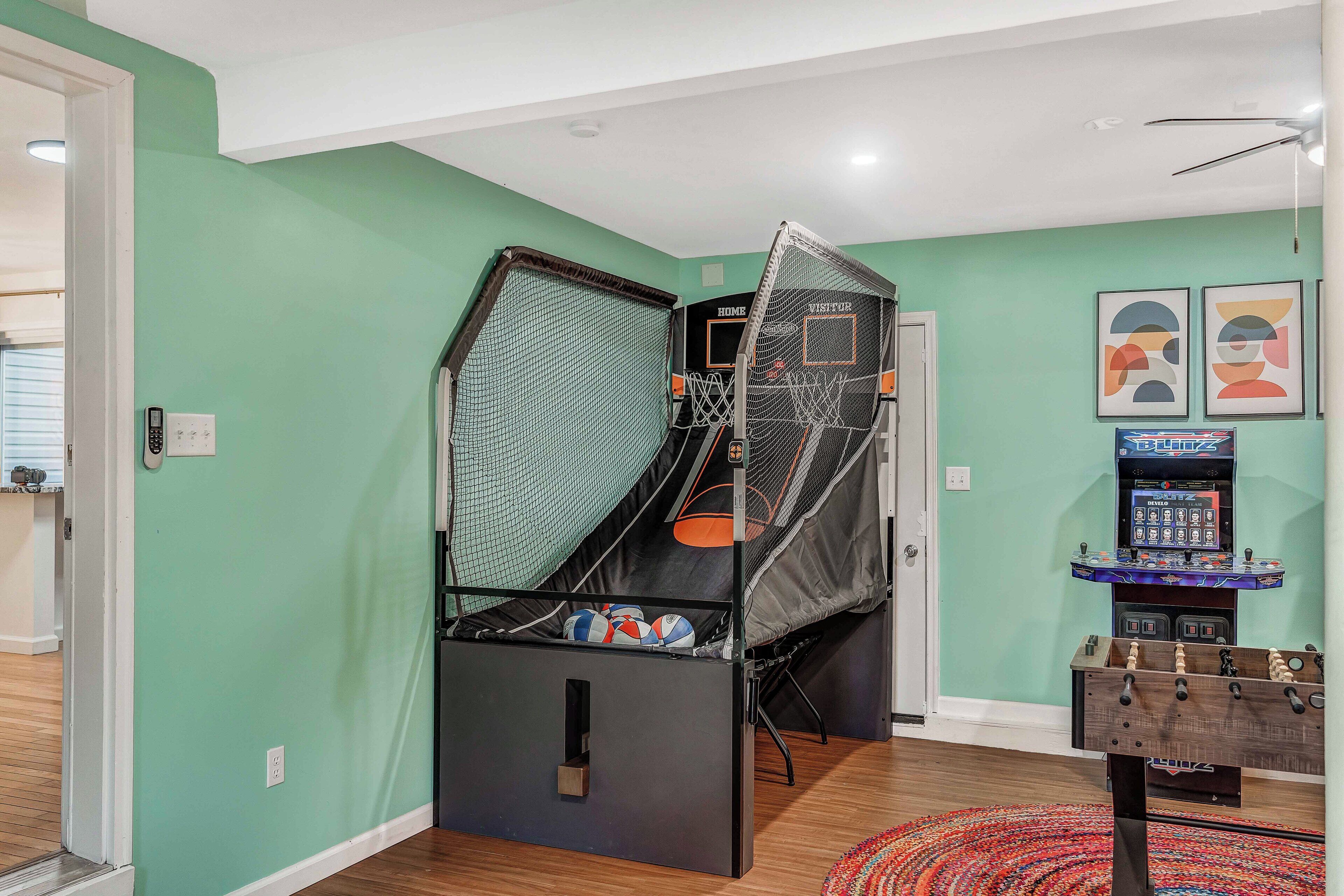 A room with a trampoline, a foosball table, and a basketball hoop.