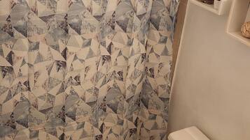 A bathroom with a patterned shower curtain, a toilet, and a sink.