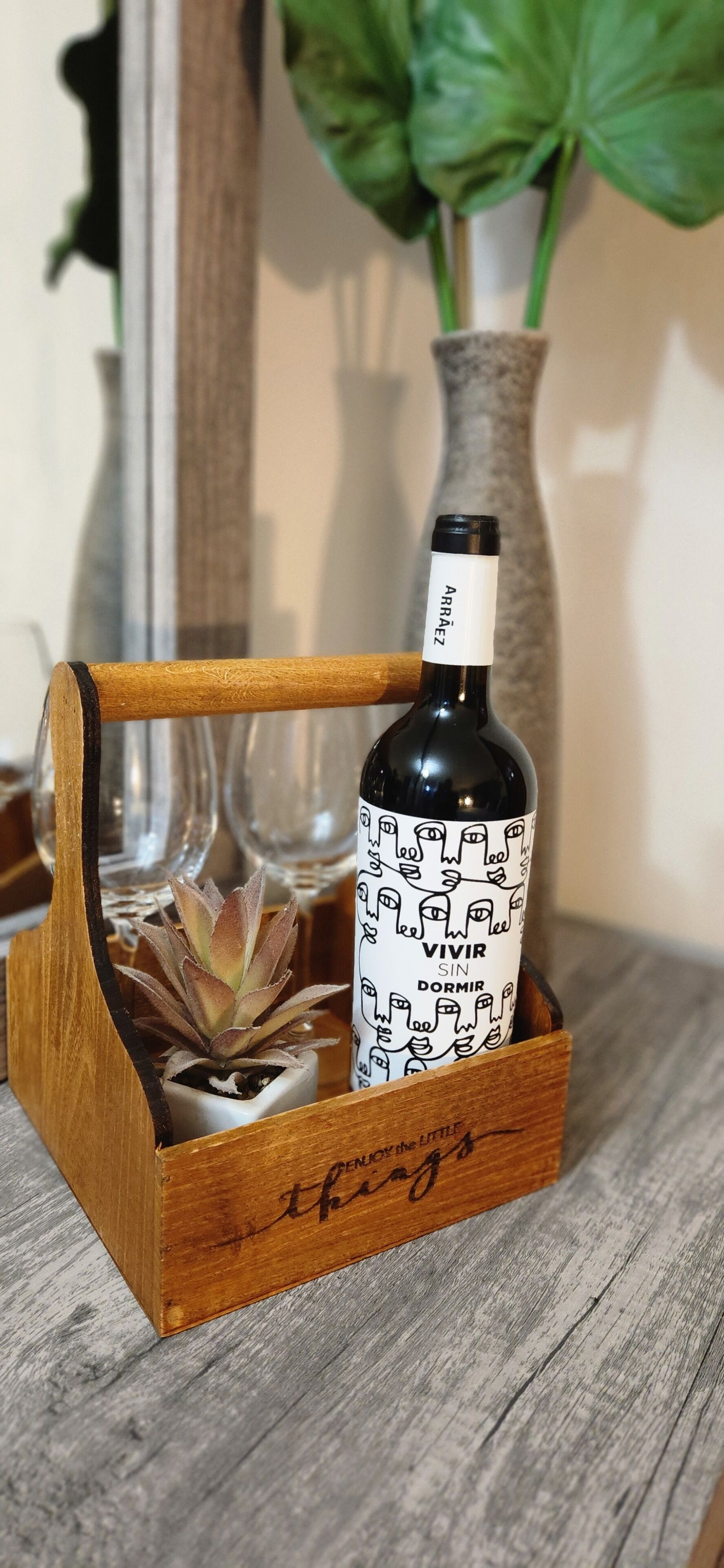 Een houten wijnrek met een fles wijn, voorzien van een etiket met de tekst 'VIVIR SIN DORMIR'.