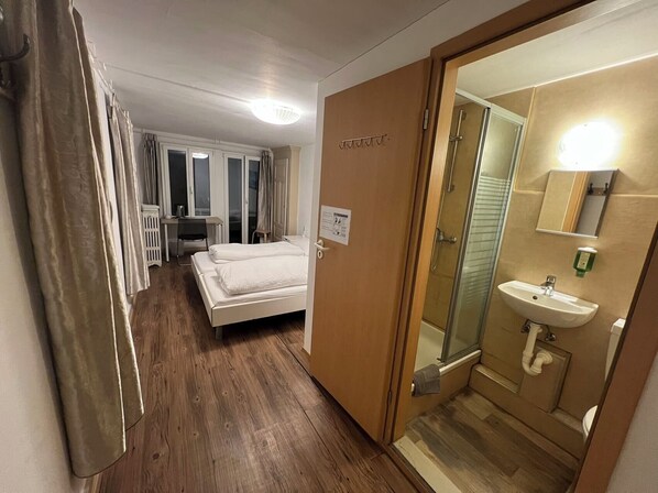 Une chambre d’hôtel avec un lit, un bureau, une douche et une salle de bain.