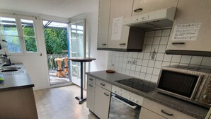 A kitchen with a stove, oven, microwave, and a window overlooking a garden. - Interlaken Linda Inn Lodge (Interlaken)