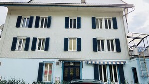 A multi-story building with a flat roof, white exterior walls, and blue shutters on the windows. - Interlaken Linda Inn Lodge (Interlaken)