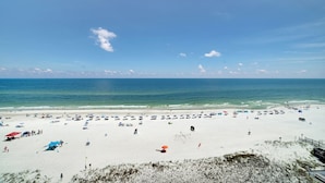 Ein Strand mit weißem Sand, blauem Himmel und ruhiger See.