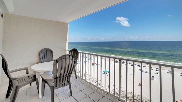 Ein Balkon mit Blick auf den Strand, einem Tisch und zwei Stühlen.