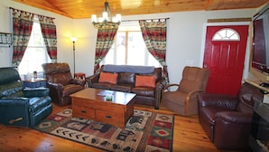 A cozy living room with leather sofas, a wooden coffee table, and patterned rugs. - Rangeley Getaway (Rangeley)