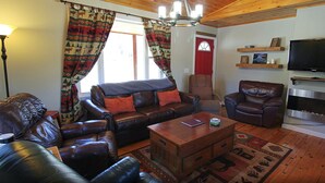A living room with a sofa, armchair, and a fireplace. - Rangeley Getaway (Rangeley)