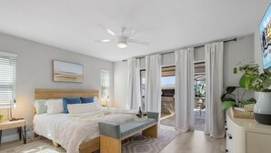 A modern bedroom with a bed, bedside table, and a view to the outside.