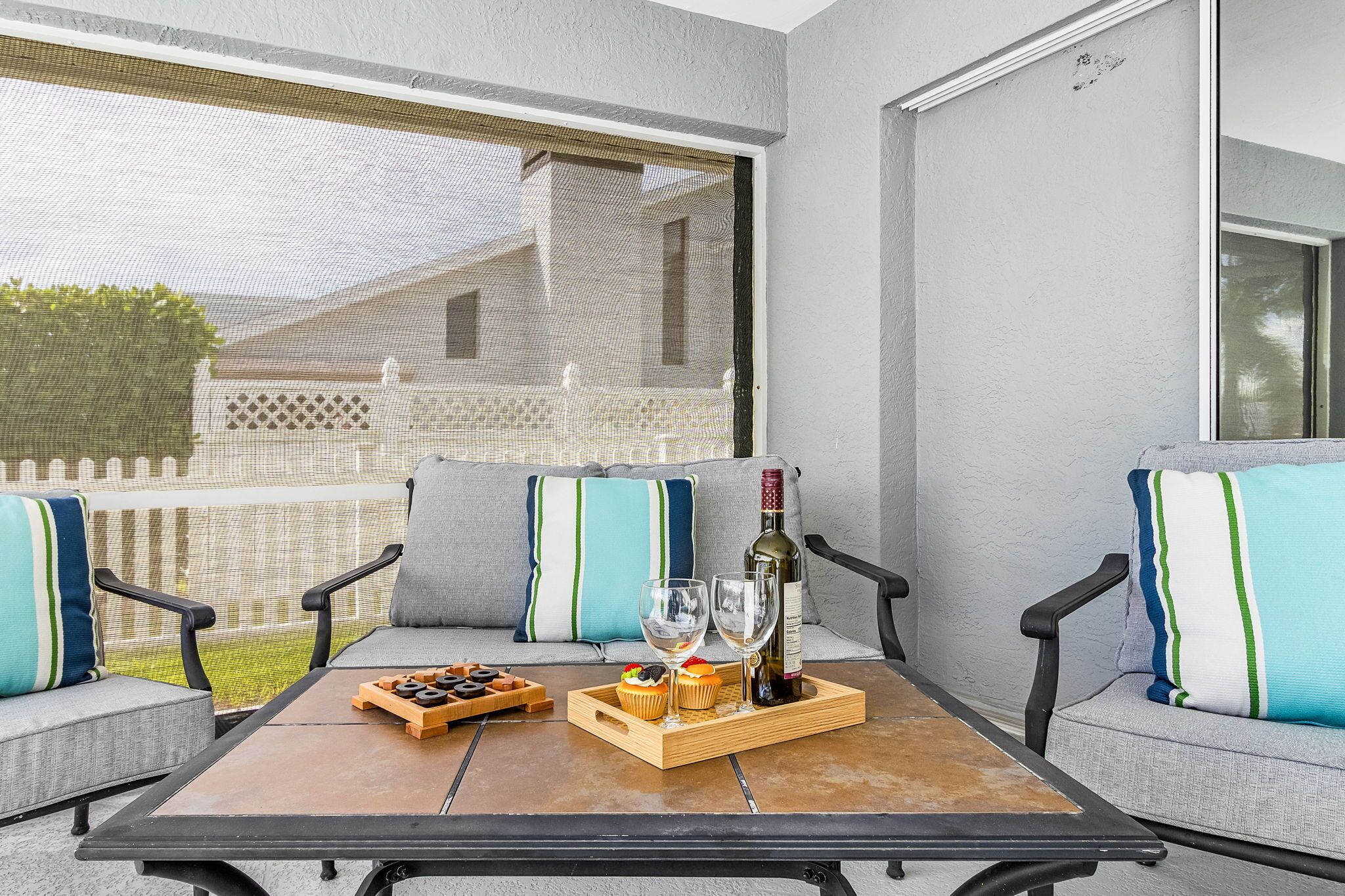 A patio with a table set for two, featuring a bottle, glasses, and snacks.