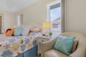 Quarto de hotel com cama, mesa de cabeceira, abajur e cadeira.