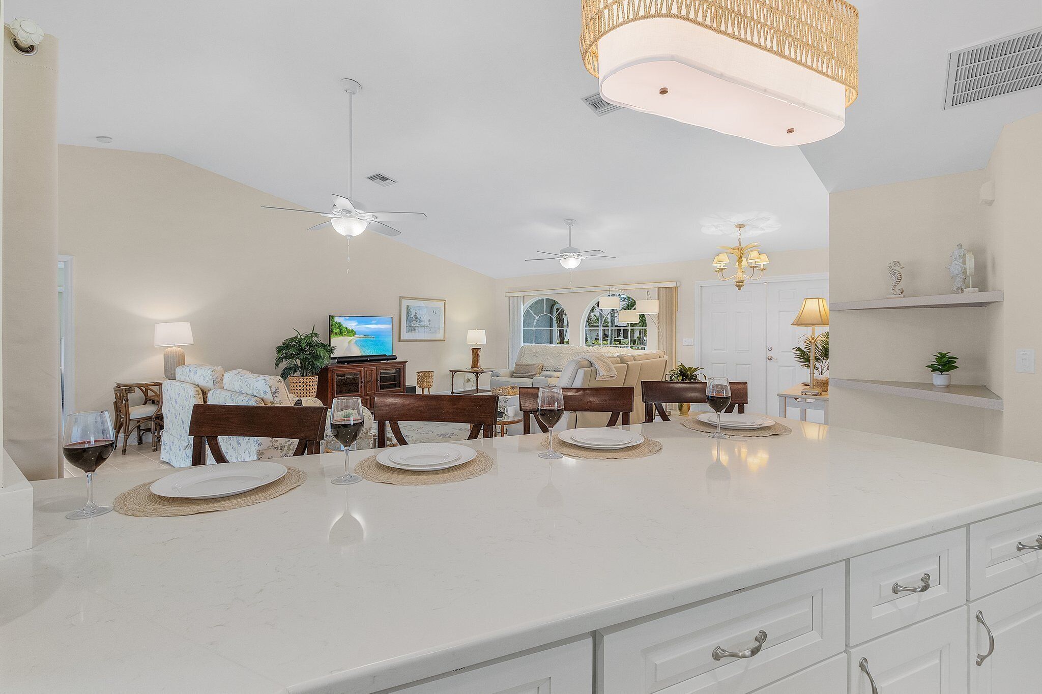 A spacious kitchen with a large island, ceiling fans, and pendant lighting.