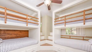 Ein Zimmer mit zwei Etagenbetten, einem Deckenventilator und einem Spiegel.