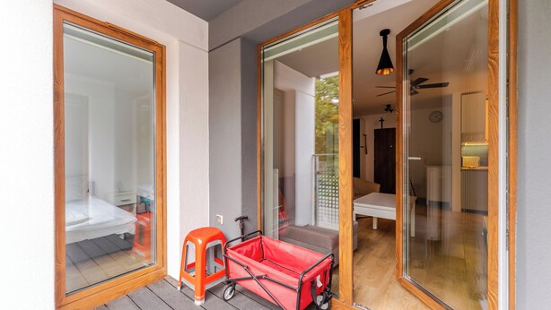 A room with a bed, a small orange stool, and a red luggage cart.