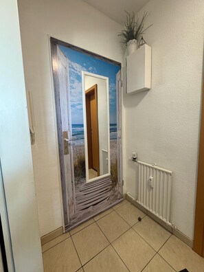 Een gang met een deur die leidt naar een kamer met een muurschildering van een strand.