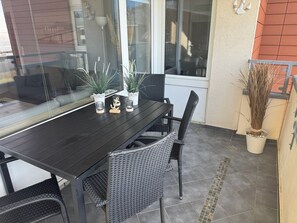 A dining area with a dark wooden table, wicker chairs, and potted plants.