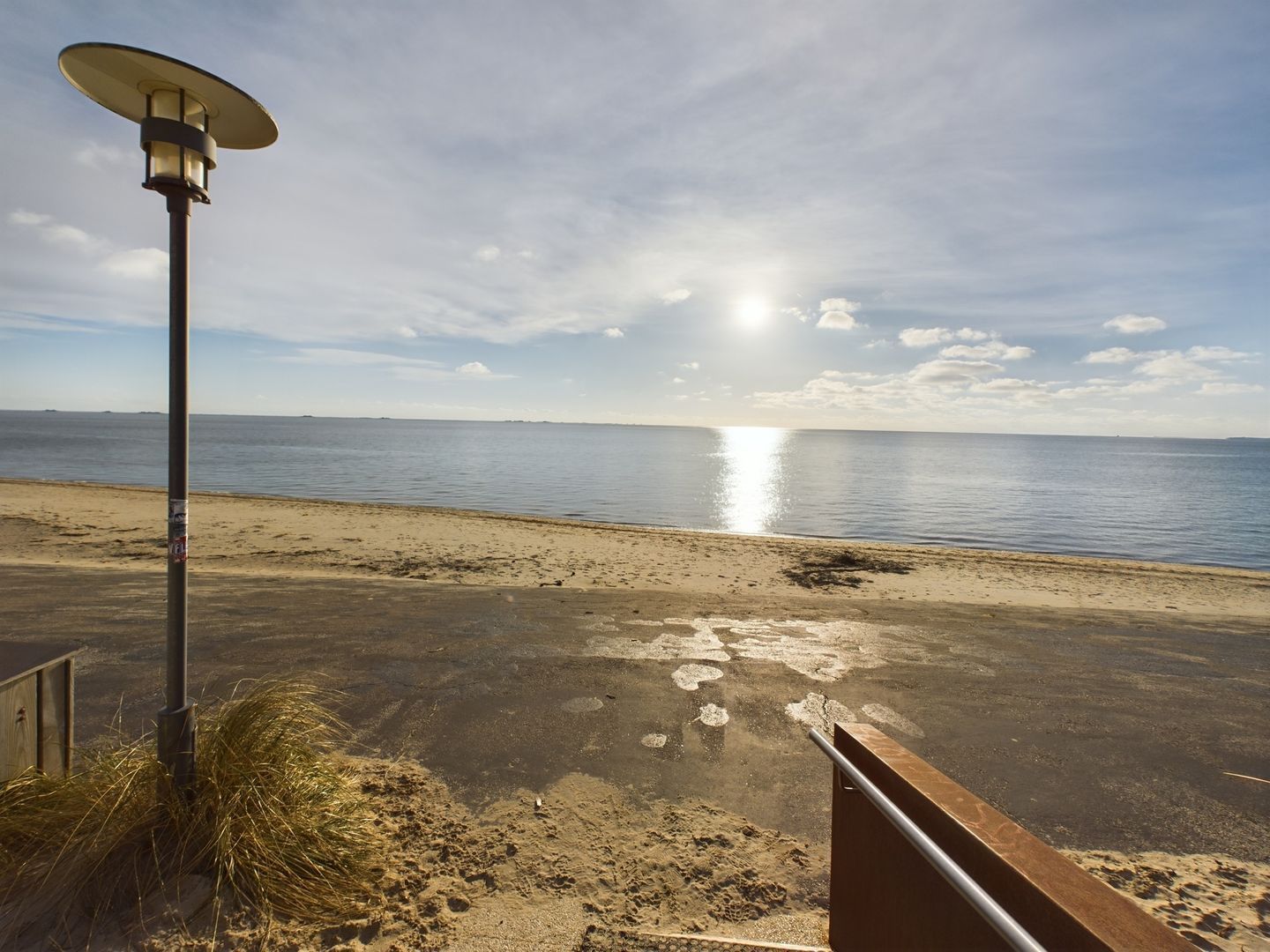 Une plage avec un lampadaire et une rambarde en métal.