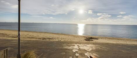 A beach with a lamp post and a metal railing.