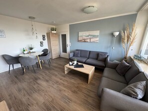 Una sala de estar moderna con un sofá gris, una mesa de centro y un comedor con sillas y una mesa.