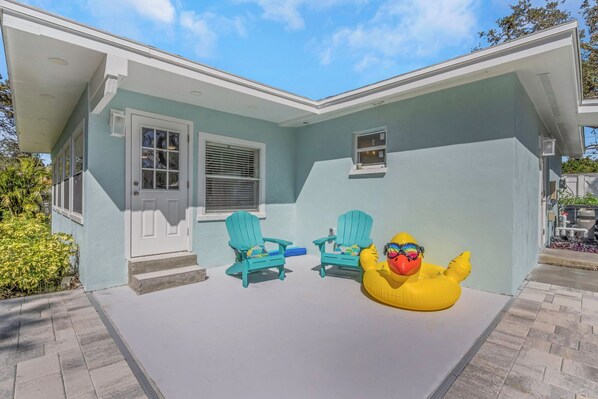 Una casa de color azul claro, con una puerta principal blanca y dos sillas Adirondack turquesa en el porche.
