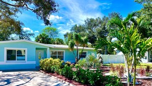 A single-story house with a light blue exterior, a front yard with various plants, and a clear blue sky. - Pool house 3 bed 2 bath, 1 mile from the beach (Largo)