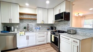 A modern kitchen with white cabinets, a stainless steel stove, and a microwave. - Pool house 3 bed 2 bath, 1 mile from the beach (Largo)