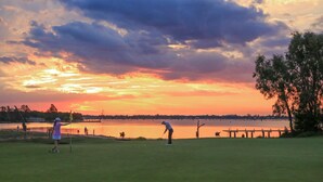 A golf course at sunset with a view of the water and trees. - D3 Ski Ranch. 5-bedroom waterfront home and private jetty. (Bundalong)