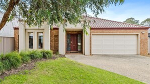 A two-story house with a front door, a garage, and a small front yard with grass and plants. - D3 Ski Ranch. 5-bedroom waterfront home and private jetty. (Bundalong)