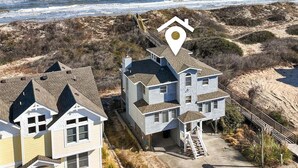 Una zona residencial costera con dos casas, una con un porche visible y una escalera que lleva a la entrada.