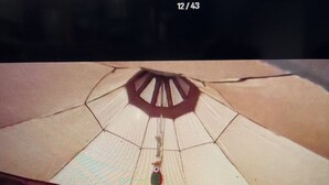 Ein Zimmer mit zwei Betten, einer blauen und weißen Bettdecke mit Muster und einer großen, paraplu-ähnlichen Konstruktion in der Mitte.
