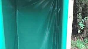 Ein kleiner, abgeschlossener Raum mit grüner Innenausstattung und einer Metalldür.