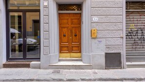 A building entrance with a double wooden door, a glass door with a metal frame, and a number '37' sign on the wall. - L'angolo dell'arte by MMega (Firenze)