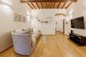 Una sala de estar con un sofá curvo, un televisor de pantalla plana y techo de madera.
