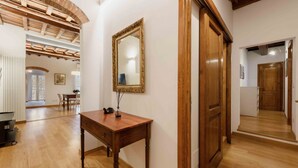 A hallway with wooden flooring, a wooden door, and a mirror on the wall. - L'angolo dell'arte by MMega (Firenze)