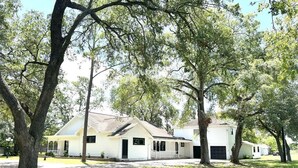 A row of white single-story houses with attached garages, surrounded by lush green lawns and large trees.