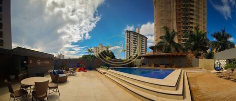 Una piscina al aire libre, sombrillas, sillones reclinables de piscina