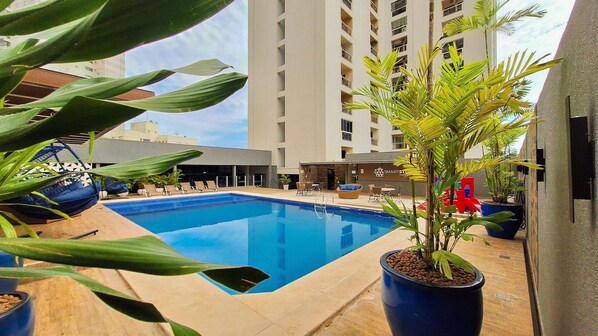 Una piscina al aire libre, sombrillas, sillones reclinables de piscina