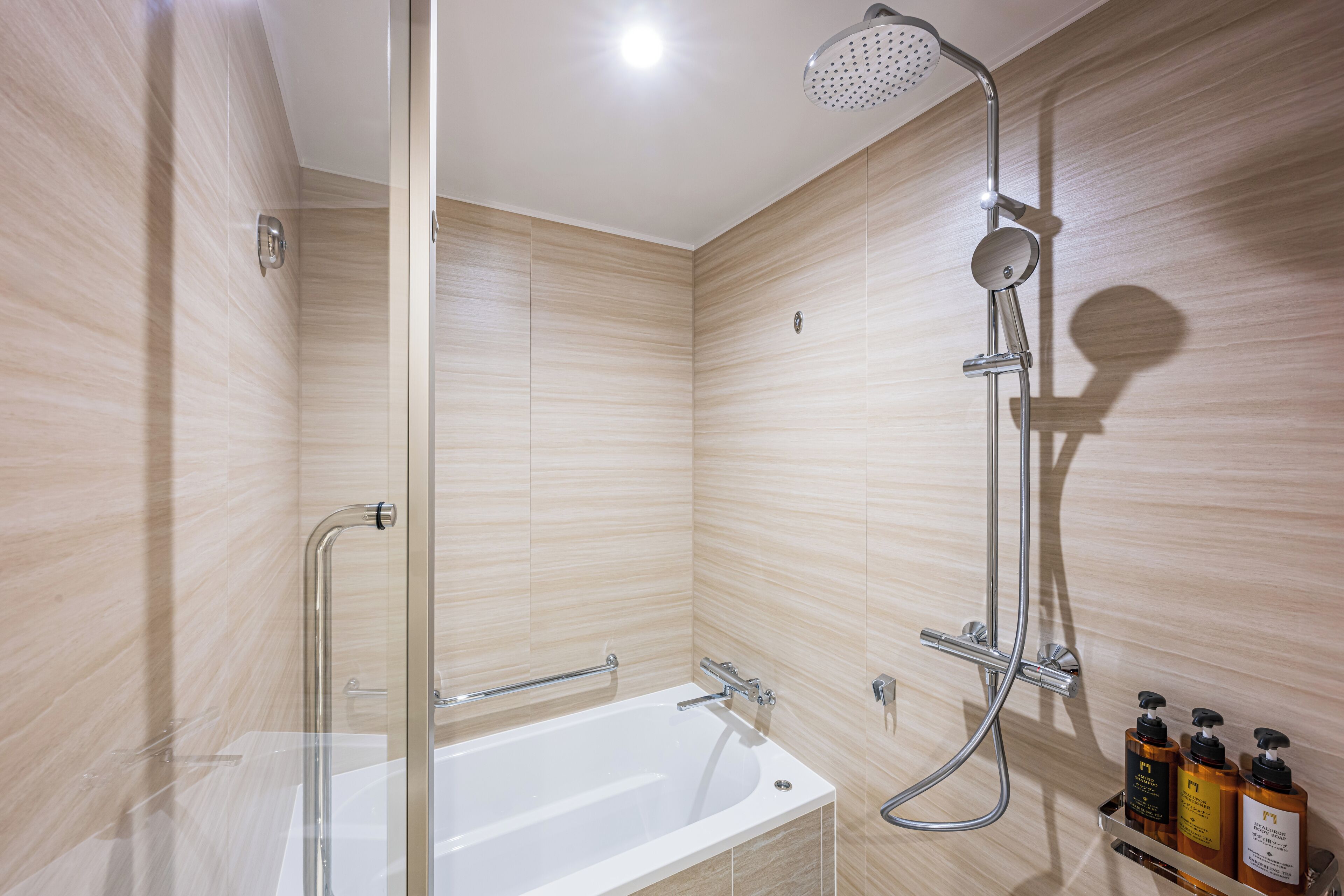 Een moderne badkamer met een douchecabine van glas, een vrijstaand bad en een plank met toiletartikelen.