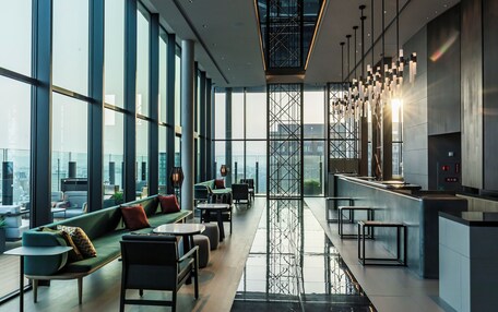 A modern interior with large windows, a central seating area, and a kitchen counter.