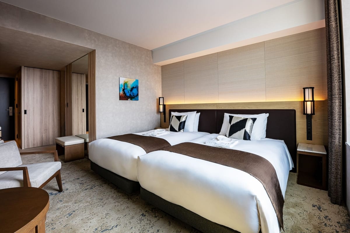 Quarto de hotel com cama grande, escrivaninha, cadeira e um quadro na parede.