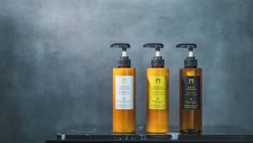Three bottles of hair care products on a reflective surface against a grey background.