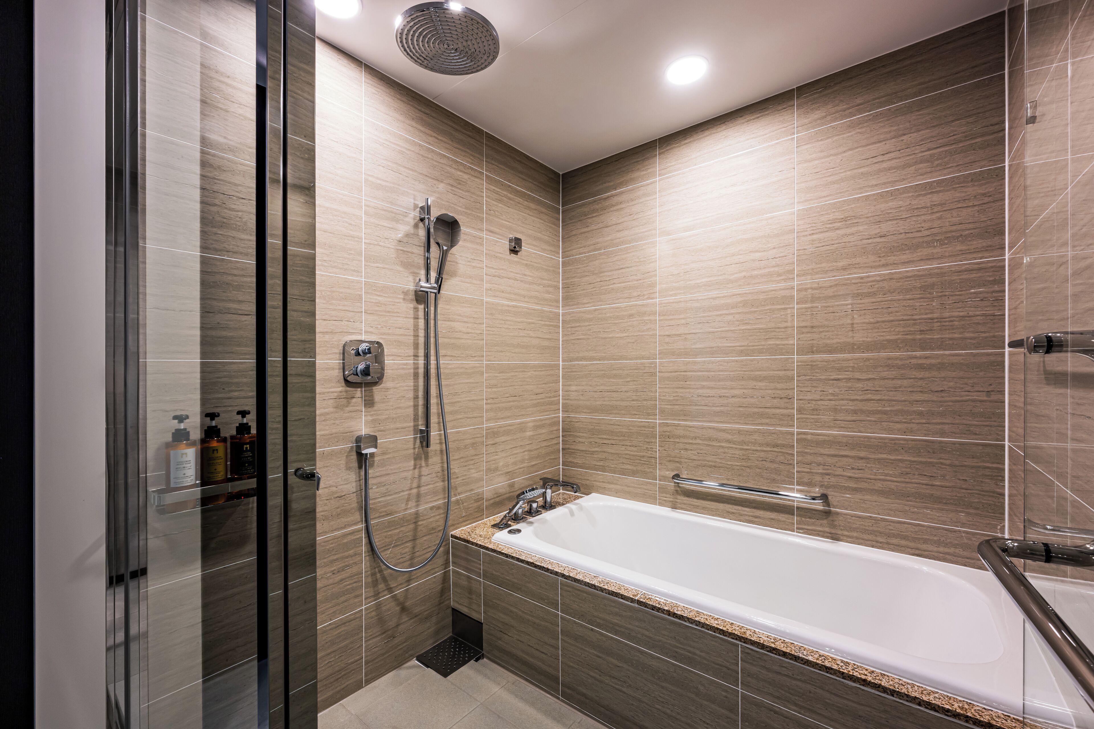 Un bagno moderno con cabina doccia in vetro, vasca freestanding e WC a muro.