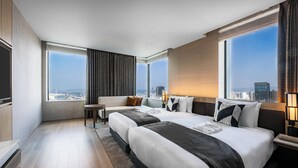 A modern hotel room with two large beds, a seating area, and large windows offering city views. - THE GATE HOTEL FUKUOKA by HULIC (Fukuoka)