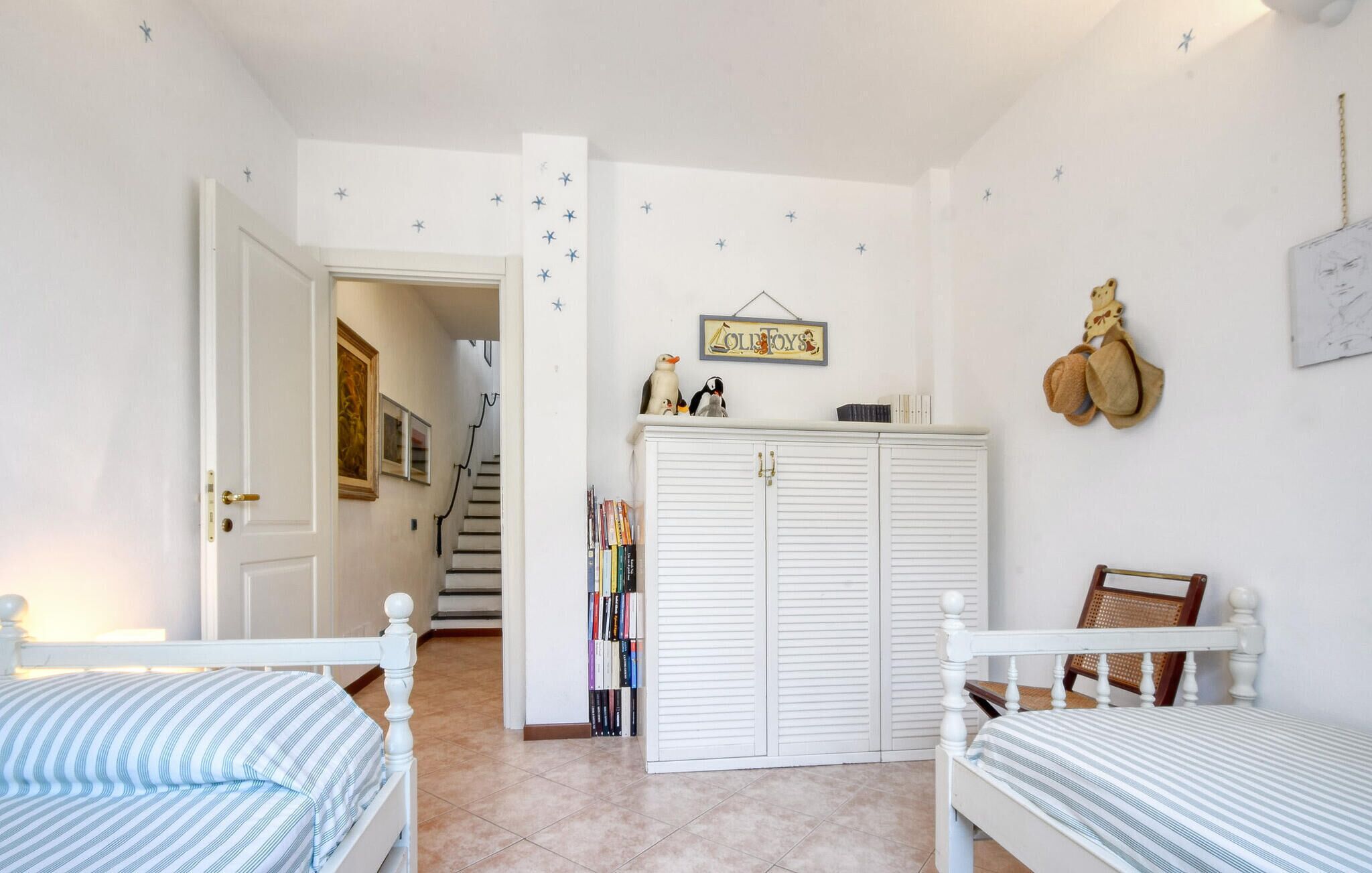 Ein Schlafzimmer mit zwei Einzelbetten, einem Kleiderschrank, einem Bücherregal und einer Treppe, die in einen anderen Raum führt.
