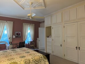 Een slaapkamer met een bed, een bureau, een stoel, een plafondventilator en een kledingkast.