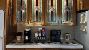A kitchen with wooden cabinets, a coffee maker, a kettle, and a mug on the counter.
