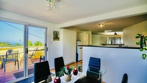 Un espace repas avec une table en verre, des chaises et une vue sur l’extérieur.