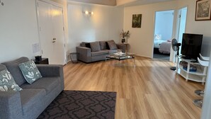 Un salon moderne avec un canapé gris, une table basse et un meuble pour la télévision, sur lequel est posée une télévision à écran plat.
