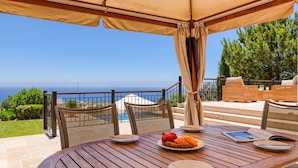 A wooden table with a pomegranate and orange slices, a chair, and a view of the sea. - Elegant Villa Retreat with Infinity Pool & Scenic Views (Paphos)