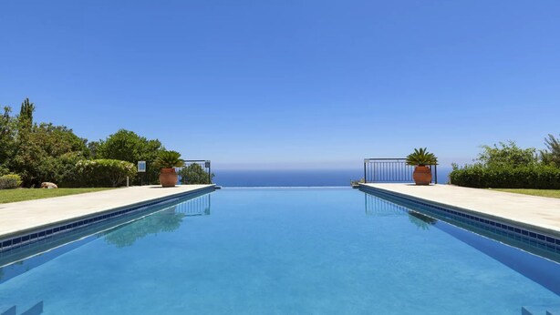 A clear blue sky above a rectangular swimming pool with a view of the ocean. - Elegant Villa Retreat with Infinity Pool & Scenic Views (Paphos)
